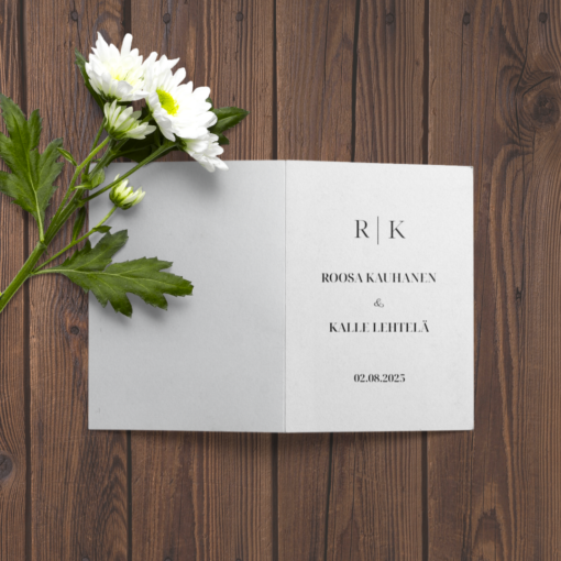 Taitettu A5-hääkutsu puupinnalla, koristeena valkoisia kukkia – personoitu etusivu nimillä ja hääpäivämäärällä.