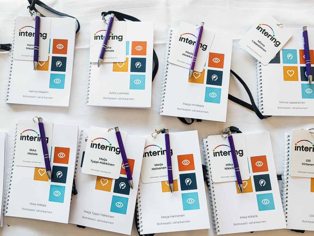 öydälle aseteltuja Intering-tapahtuman muistivihkoja, kyniä ja nimikylttejä osallistujille.