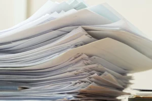 Suuri pino papereita ja asiakirjoja toimistopöydällä.