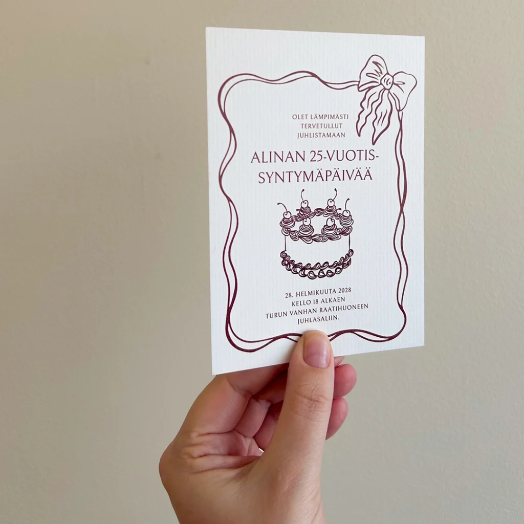 Lähikuva syntymäpäiväkutsusta, jossa koristeellinen kehys ja kakkukuva